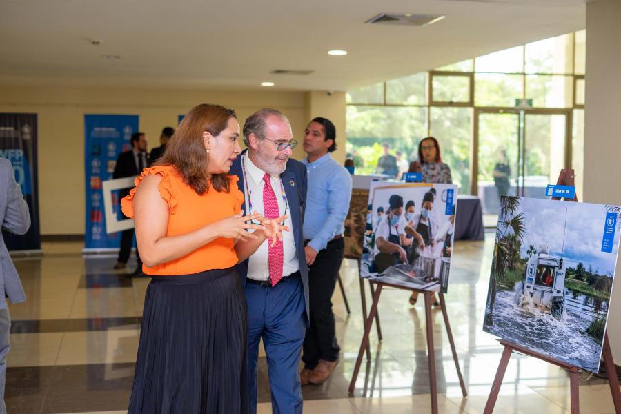 Una mujer y un hombre observan fotografías de una exposición fotográfica sobre el trabajo que realiza el Programa Mundial de Alimentos en El Salvador.