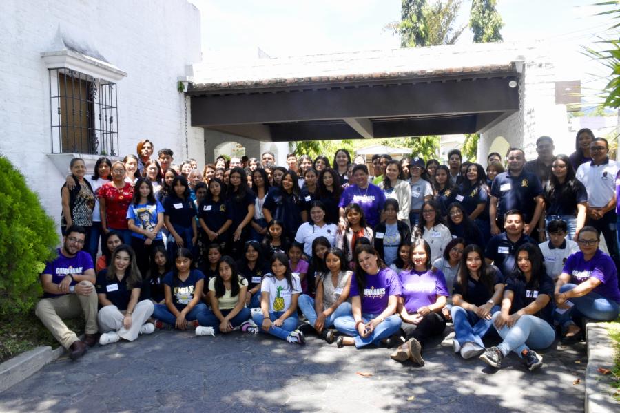 Foto de grupo con todas las personas que participaron en el diálogo intergeneracional, algunas de pie y otras sentadas en el suelo.