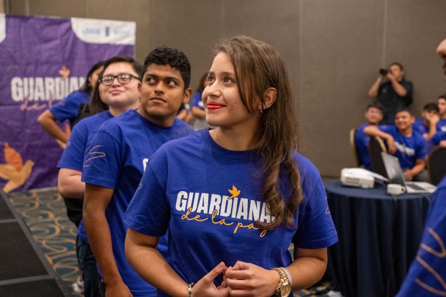 En primer plano, Fernanda Retana, representante de las unidades juveniles, escucha una de las intervenciones en el foro. Al fondo, otros jóvenes también escuchando atentamente.