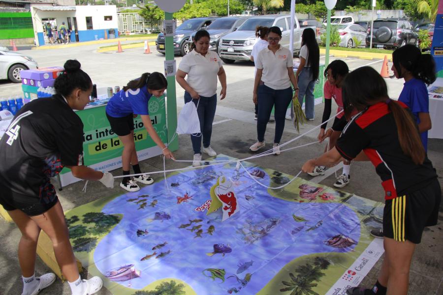 Cinco niñas participan en un juego de la feria interactiva en el que juntas deben mover unas cuerdas para atrapar un pez de cartón.