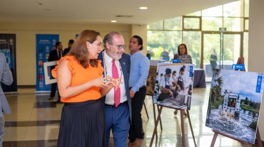 Una mujer y un hombre observan fotografías de una exposición fotográfica sobre el trabajo que realiza el Programa Mundial de Alimentos en El Salvador.